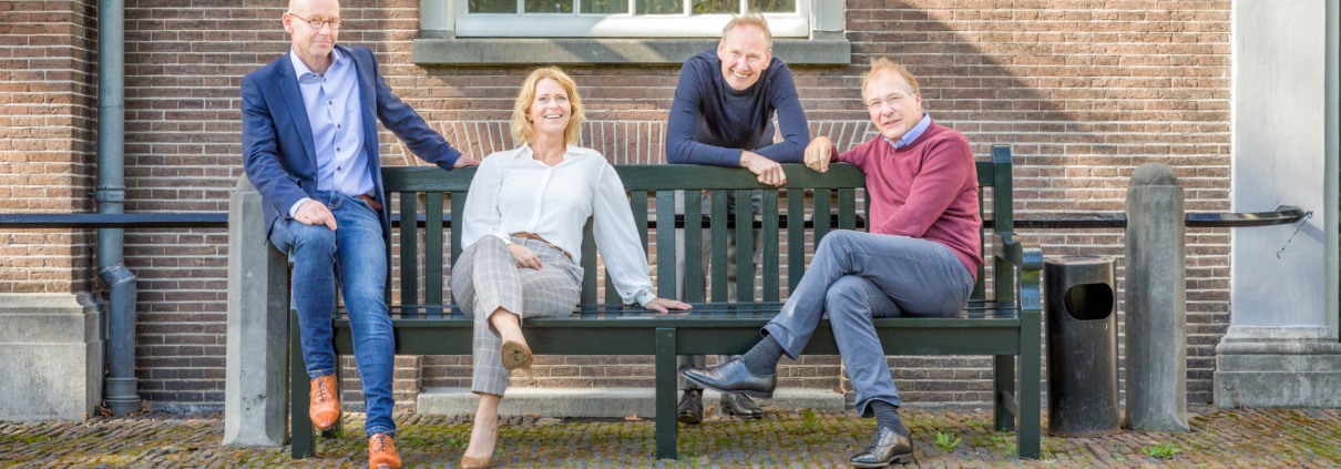 Instituut voor Zakelijke Mediation -team op een houten bank voor een oud gebouw