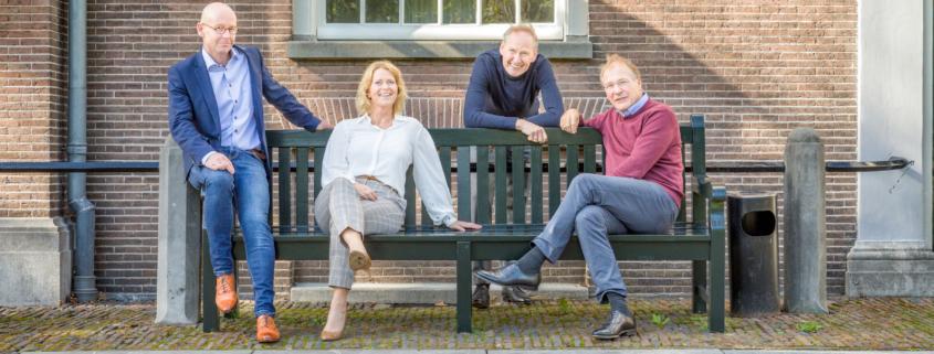 Instituut voor Zakelijke Mediation -team op een houten bank voor een oud gebouw
